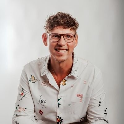 Patrick Pompös sitzt vor einer weißen Wand